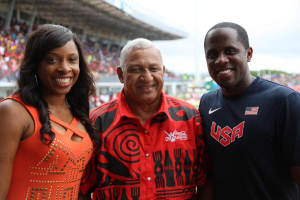 Drei Personen, die vor einem Stadion mit Zuschauern und Himmel lächeln, mit einem Coca-Cola Games 2014-Wasserzeichen.