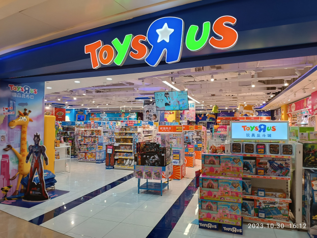 Ein Toys R Us-Laden in einem Einkaufszentrum mit Regalen voller Spielzeuge, einem Namensschild, Deckenleuchten und einem Wasserzeichen in der rechten unteren Ecke.