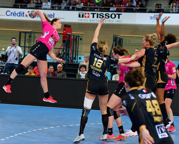 Eine Gruppe von Frauen spielt Handball auf einem Platz mit einem Ball in der Luft, und Zuschauer im Hintergrund schauen dem Spiel zu, mit einem Schild, auf dem "Futsal-Weltmeisterschaft 2019 - Bordeaux gegen Paris" steht.