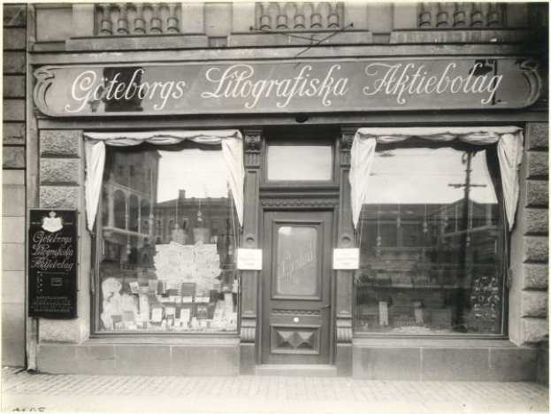 Schwarzes und weißes Foto einer Geschäftsfront in Stockholm, Schweden, mit einer Tür, Fenstern, Vorhängen und einem Schild mit der Aufschrift "Giteborgs Litografiska Aktiebolag."