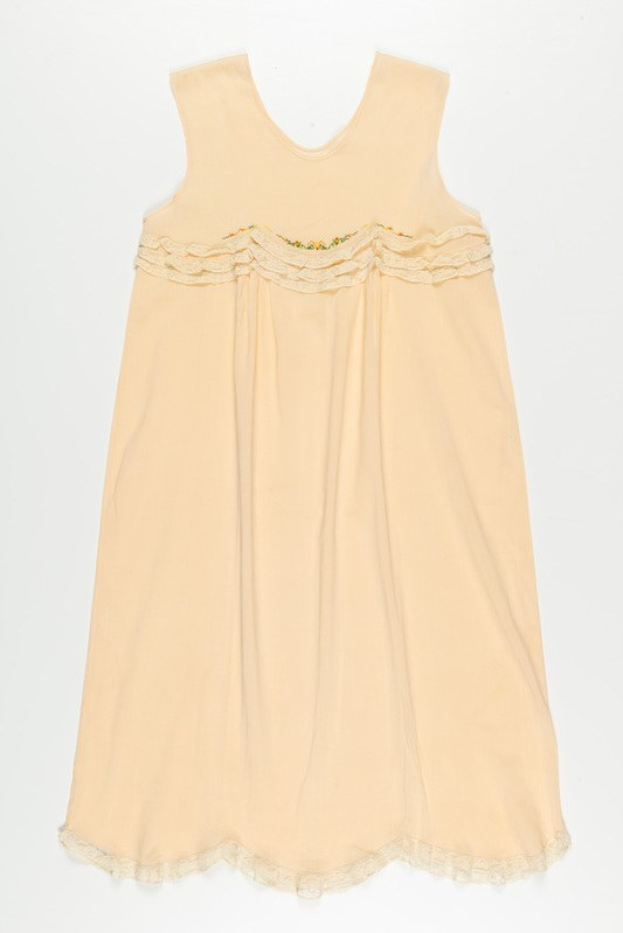 Ein cremefarbenes Nachthemd mit zarter Spitzenborte am Halsausschnitt, aus weichem, leichtem Stoff mit einem dezenten Schimmer.