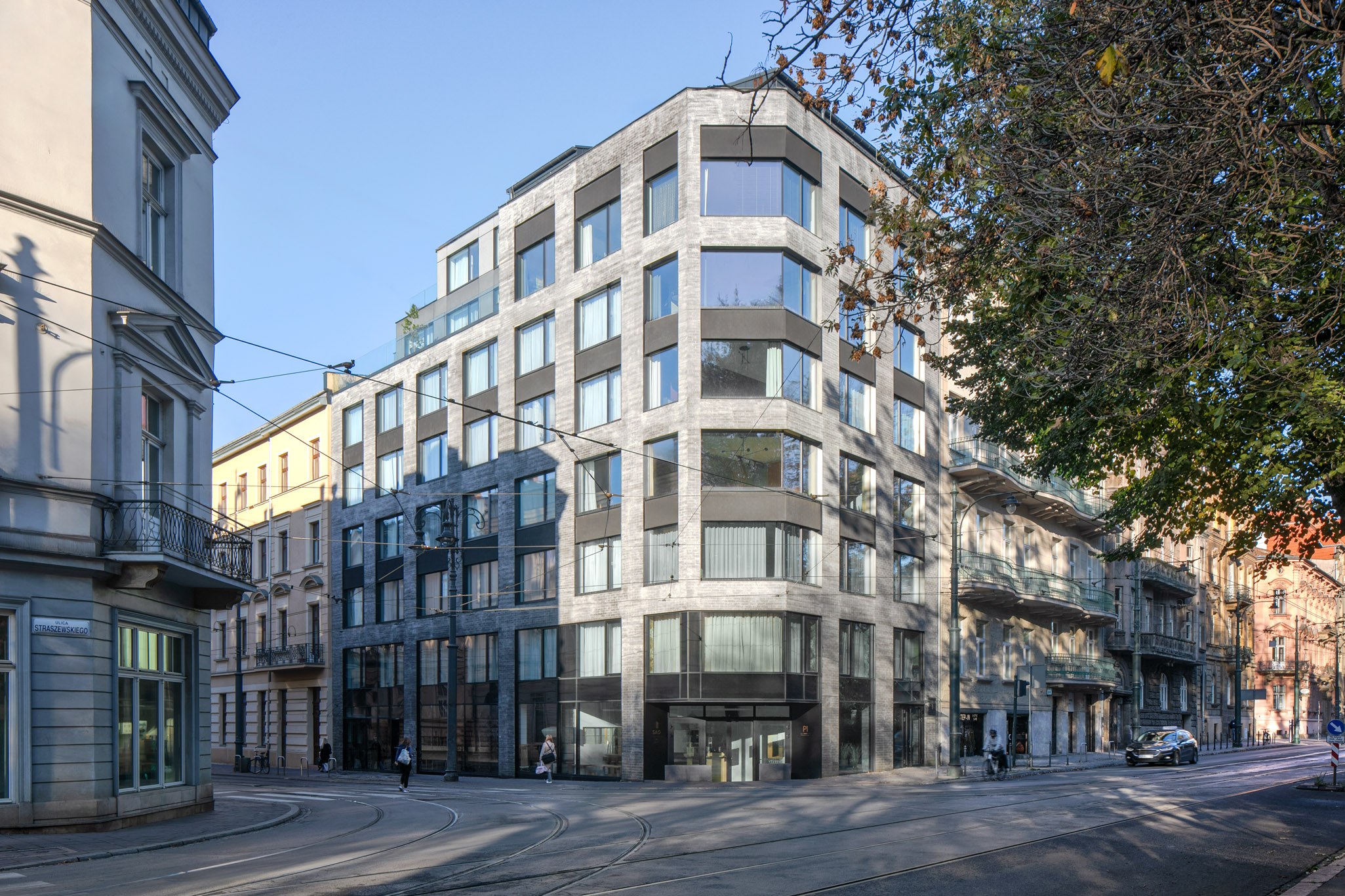 Großes modernes Bürogebäude mit zahlreichen Fenstern, umgeben von Straßeninfrastruktur, Fahrzeugen, Fußgängern, Bäumen und einem bewölkten Himmel, das als neue Firmenzentrale dient.