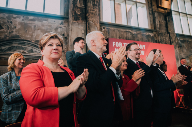 Gruppe von Menschen, die vor einer Menge jubeln und ein Banner mit der Aufschrift "Wahlsieg" hinter sich halten.