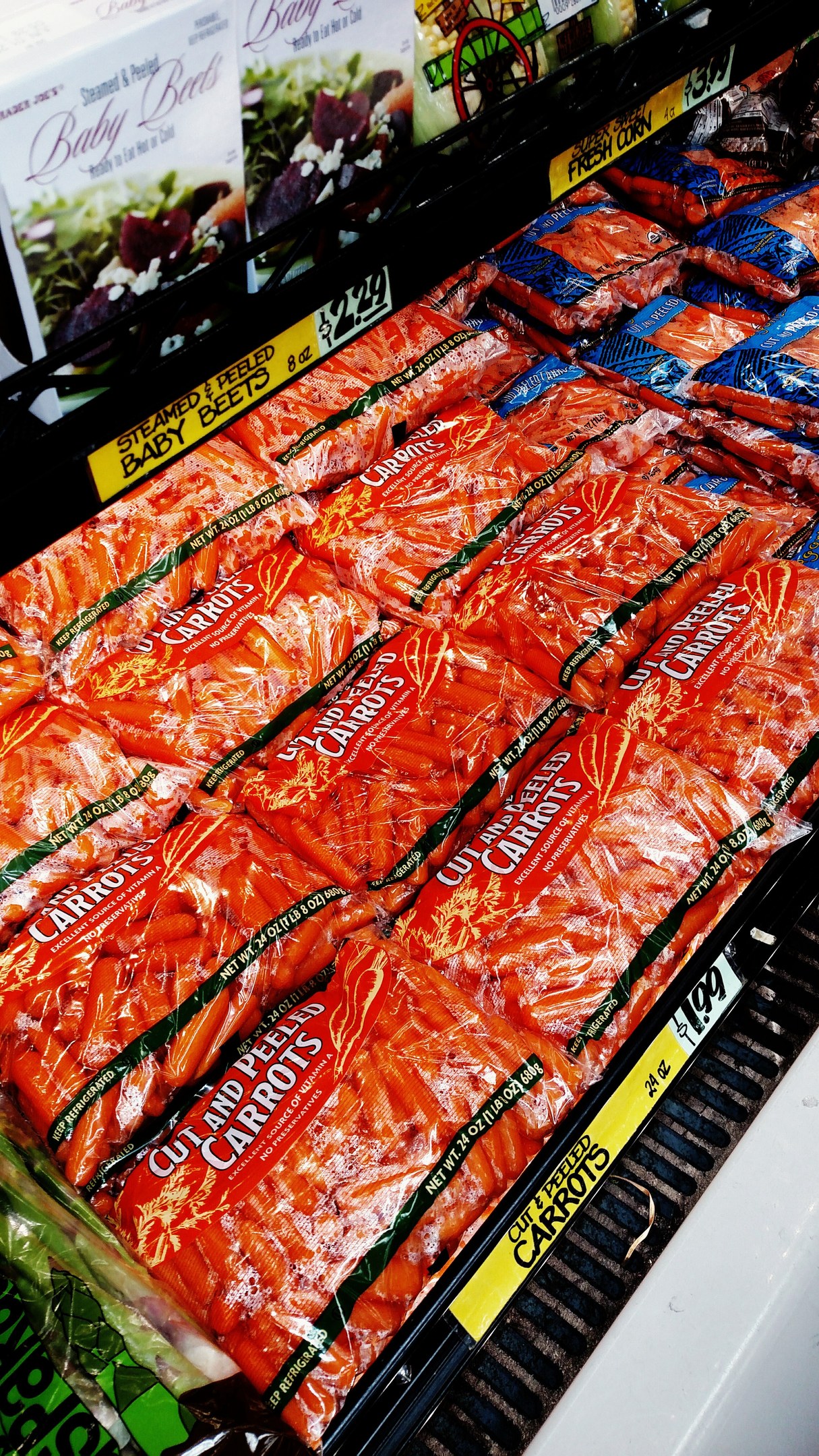 Ein Supermarktregal voller verschiedener Lebensmittel, einschließlich verpackter Gemüse mit sichtbaren Preisschildern.