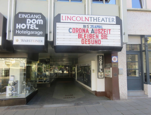 Außenansicht des Lincoln Theaters in Berlin, Deutschland, mit Glasfenstern und -türen und einer Tafel sowie einem Blick ins Innere durch den Eingang.