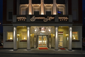 Das Essenerhof Hotel in Berlin, Deutschland, ein mehrstöckiges Gebäude mit Fenstern, Türen, Säulen, Laternen und einem Namensschild, mit einer Straße davor und Fahrzeugen auf der rechten Seite.