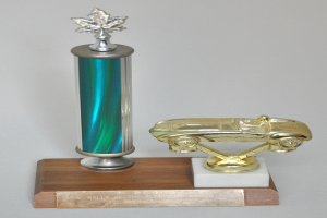 Ein glanzvolles, detailliert gearbeitetes Preisstück mit einem Miniaturauto darauf, auf einer hellen Holzplatte montiert.