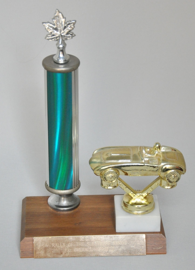 Ein glanzvolles, detailliert gearbeitetes Preisstück mit einem Miniaturauto darauf, auf einer hellen Holzplatte montiert.