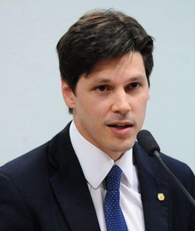 Ein Mann in Anzug und Krawatte spricht vor einer Wand in ein Mikrofon, wahrscheinlich um die Genehmigung eines Gesetzes durch die Regierung zu kommentieren.