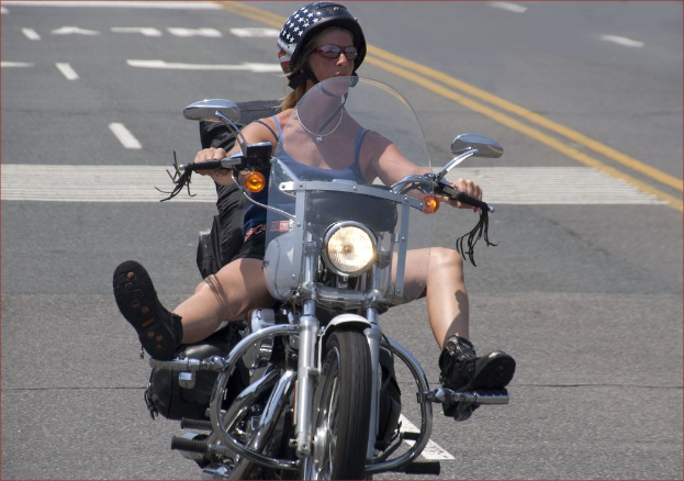 Eine Frau fährt ein Fahrrad auf einer Straße und trägt einen schwarzen Helm.