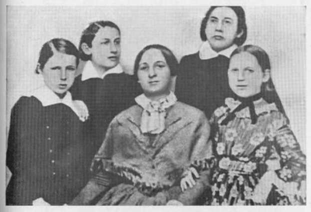 Schwarzes und weißes Foto einer Gruppe von Frauen, eine sitzt in der Mitte, mit dem Text "Die Frauenwahlrechtsbewegung" unten.