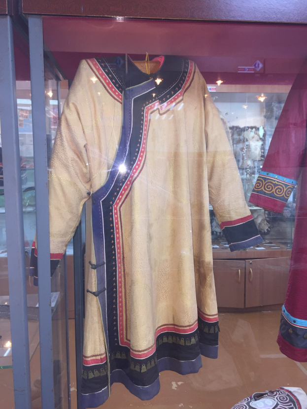 Vitrine mit verschiedenen Kostümen aus 'Der König der Löwen', einschließlich einer Puppe in einem Kleid und einer Mütze, sowie anderen thematischen Gegenständen.