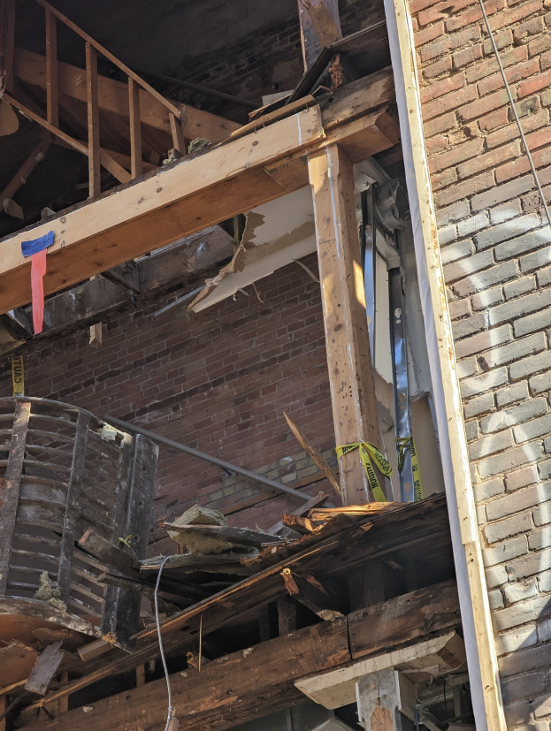 Ein teilweise abgerissenes Gebäude mit verstreuter Trömmern, zerbrochenen Fenstern und Türen, was auf die Nachwirkungen der Abrissarbeiten hindeutet.