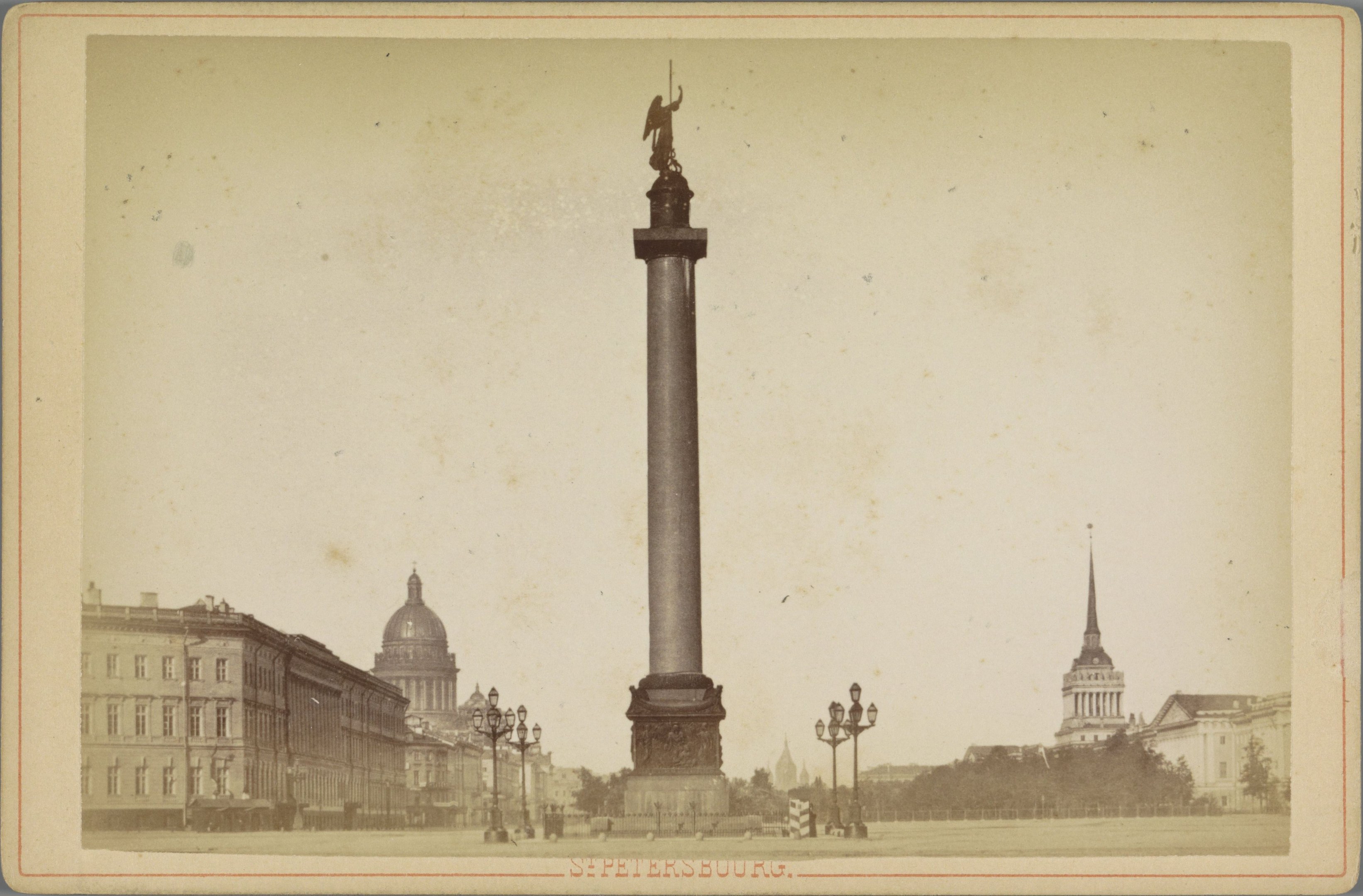 Altes Schwarz-Weiß-Foto eines Denkmals in einem städtischen Platz, umgeben von Gebäuden, Straßenlaternen, Lichtern, Bäumen und einem klaren Himmel; Text erscheint am unteren Rand.