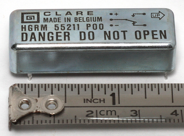 Metallkasten mit der Aufschrift "Danger Do Not Open" neben einem Lineal auf einer weißen Oberfläche.