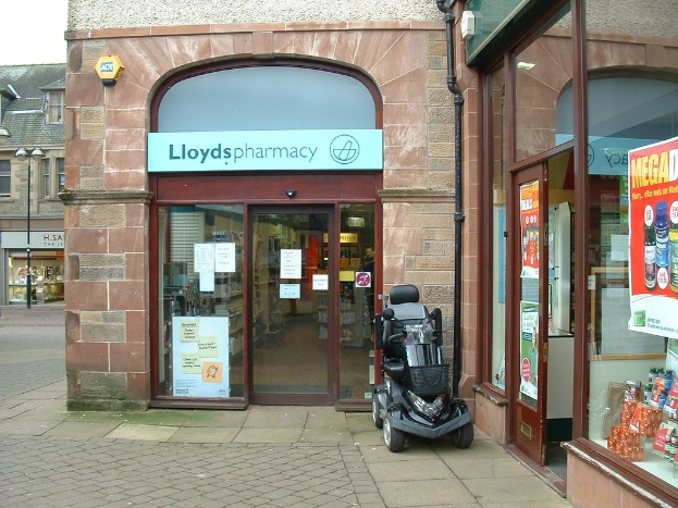 Pharmacy store mit einem Fahrzeug vorne und einem Gebäude links.