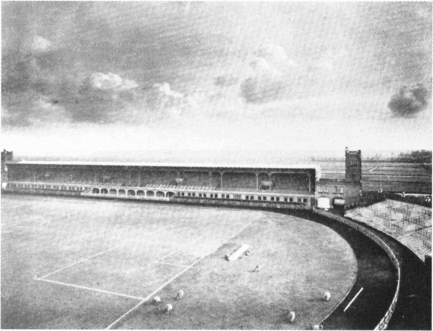 Schwarzes und weißes Foto eines Fußballfeldes mit einem Stadion im Hintergrund, umgeben von Bäumen und einem bewölkten Himmel, mit dem Text "Stoke City Football Club" unten.